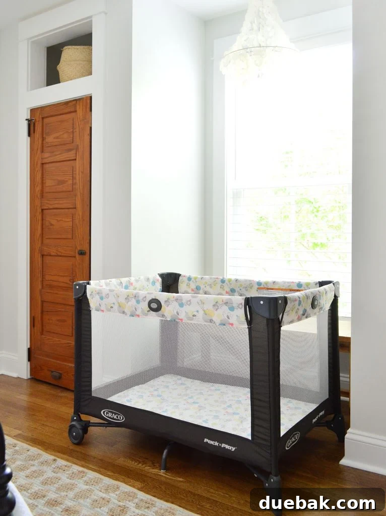 Pack N Play set up in a duplex bedroom, showing space between closets with a rug and baskets.