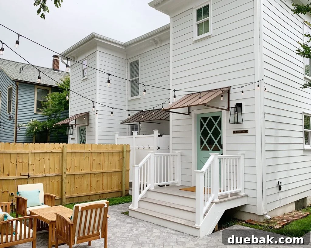 The newly renovated duplex backyard with outdoor furniture, string lights, and a charming shed. The back door is painted Pale Patina by Sherwin Williams, enhancing the rental's curb appeal.