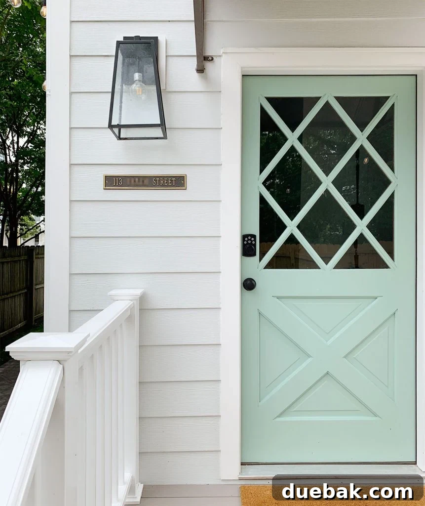 Duplex back door featuring a clear address plaque, a secure keypad lock, and a charming porch lantern, with the door painted in Pale Patina by Sherwin Williams.