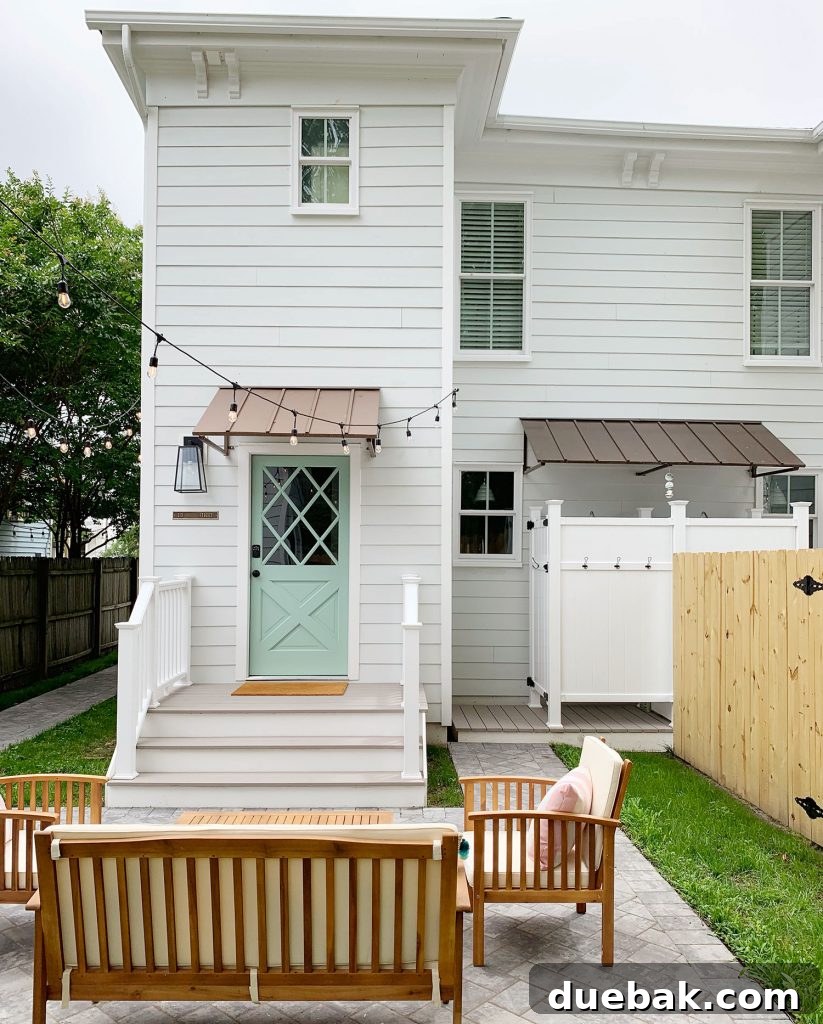 Wider shot of the duplex backyard, showing the dividing fence, essential outdoor showers under an awning, and a full view of the renovated space with outdoor furniture.