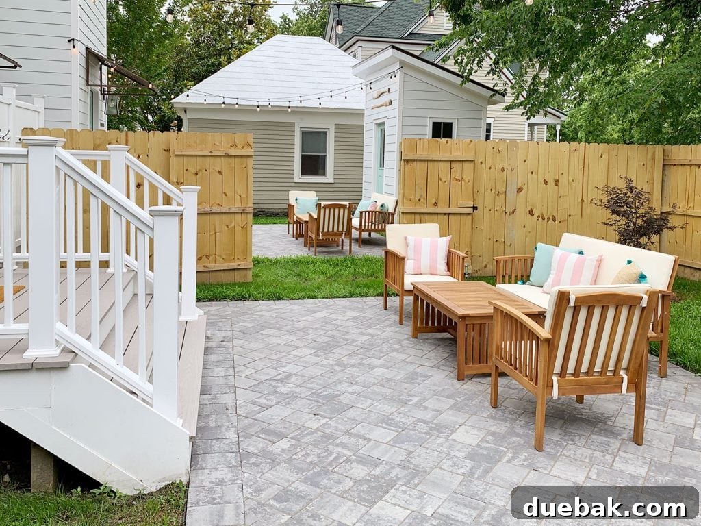 Duplex backyards with the connecting gate open, creating one large shared outdoor space, complete with comfortable furniture and inviting string lights.