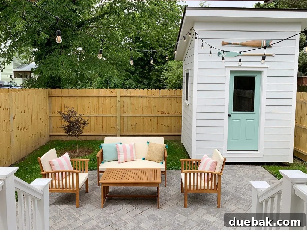 Inviting duplex backyard with comfortable outdoor seating, ambient string lights, and a neatly manicured lawn, enclosed by a sturdy wooden privacy fence.