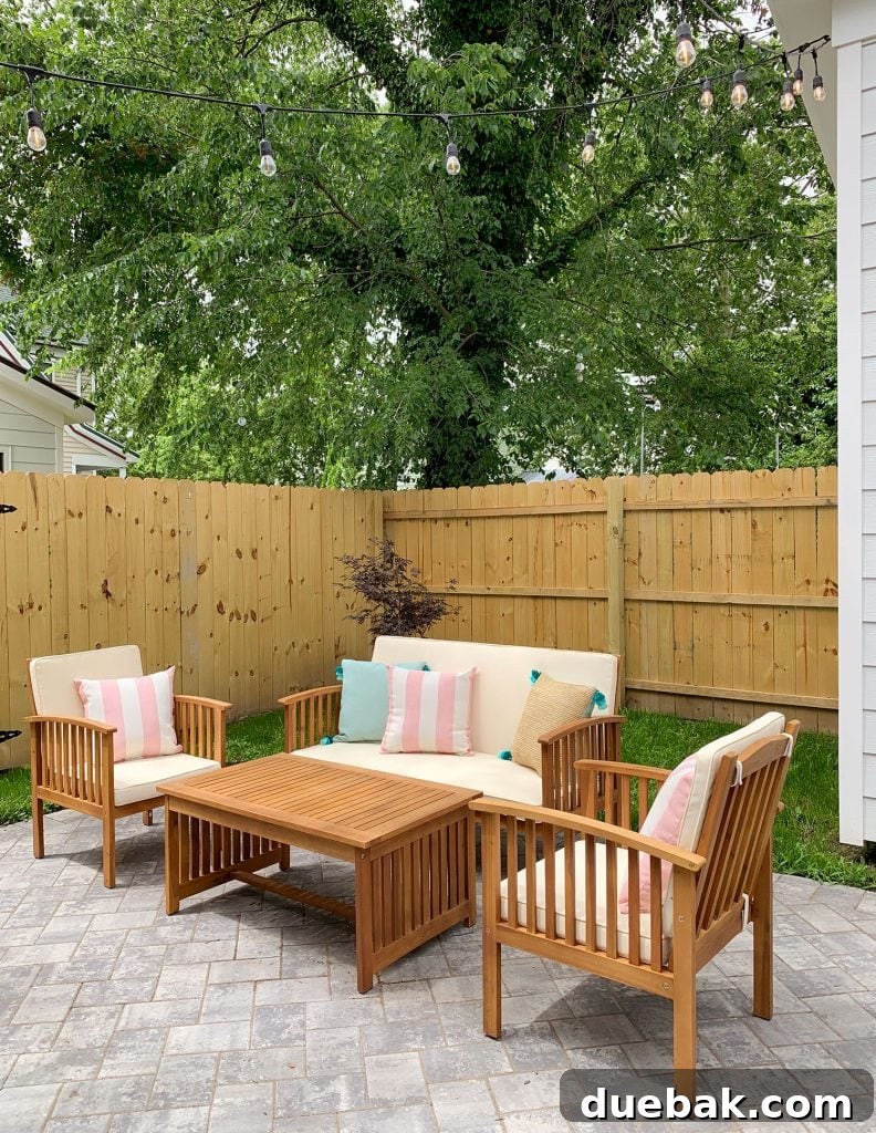 Night shot of the duplex backyard, beautifully illuminated by string lights, highlighting the comfortable outdoor furniture and decorative pillows.