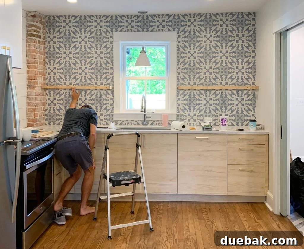 Man Holding Up Shelf Support Brackets Against Tile Backsplash