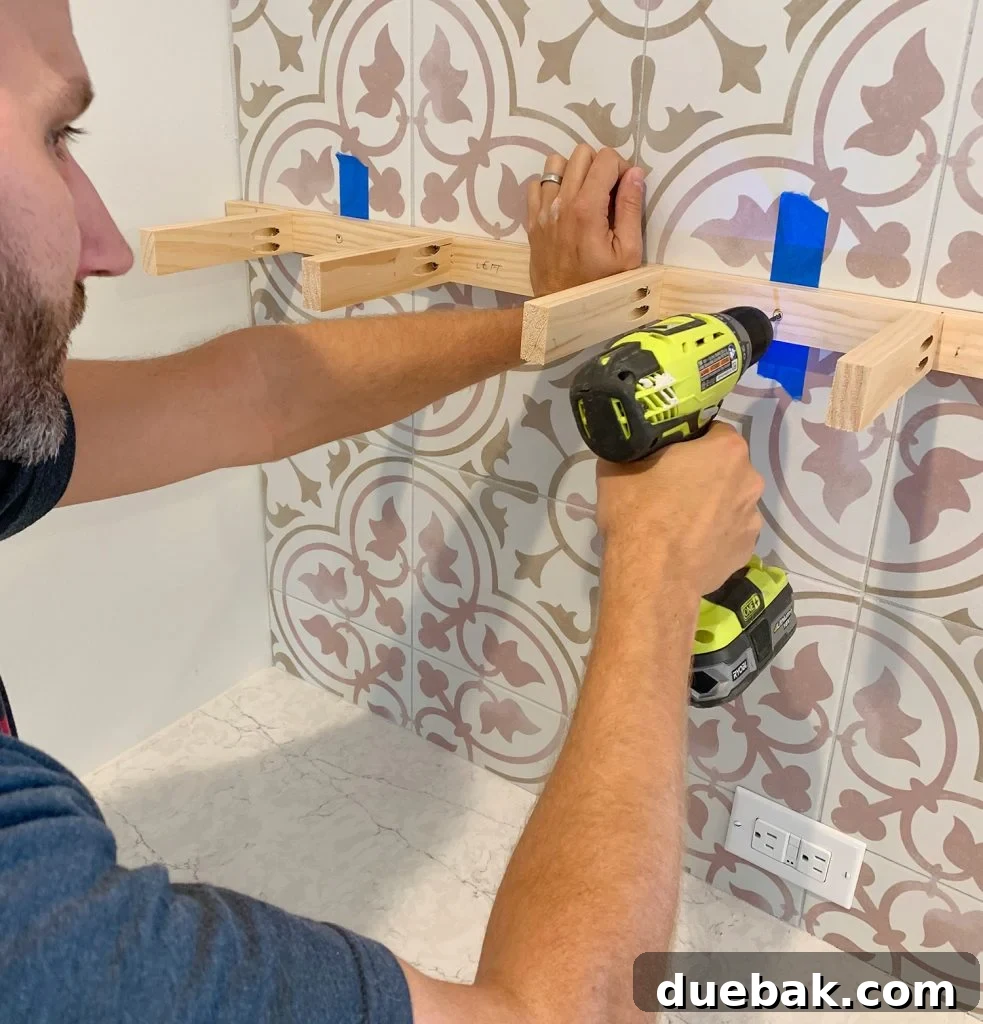 Man Drilling Through Tile Backsplash With Wood Support Bracket Held Up
