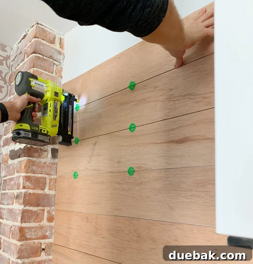 Nail Gun Securing Wood Panels To Backsplash Using Tile Spacers