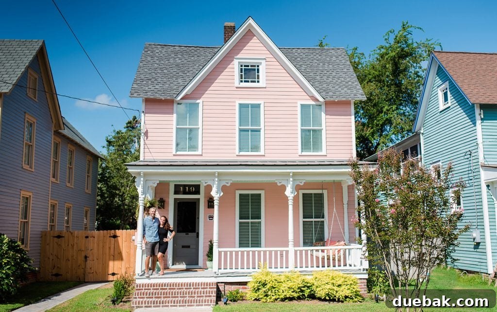 The Pink House Unveiling Its Unexpected History 11 A charming photo of the beach house entrance with the family, showcasing the newly painted door and the historic plaque.