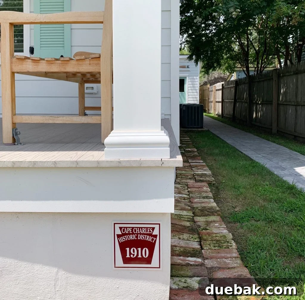 The Pink House Unveiling Its Unexpected History 7 A close-up view of the duplex historic plaque, showing its placement on the foundation with lush greenery.