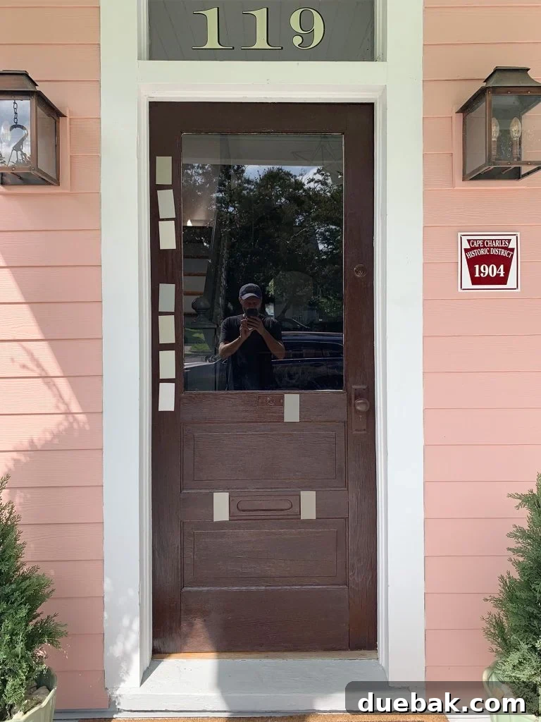 The Pink House Unveiling Its Unexpected History 9 A wider shot of the beach house porch, featuring the new door color, planters, and other decorative elements.