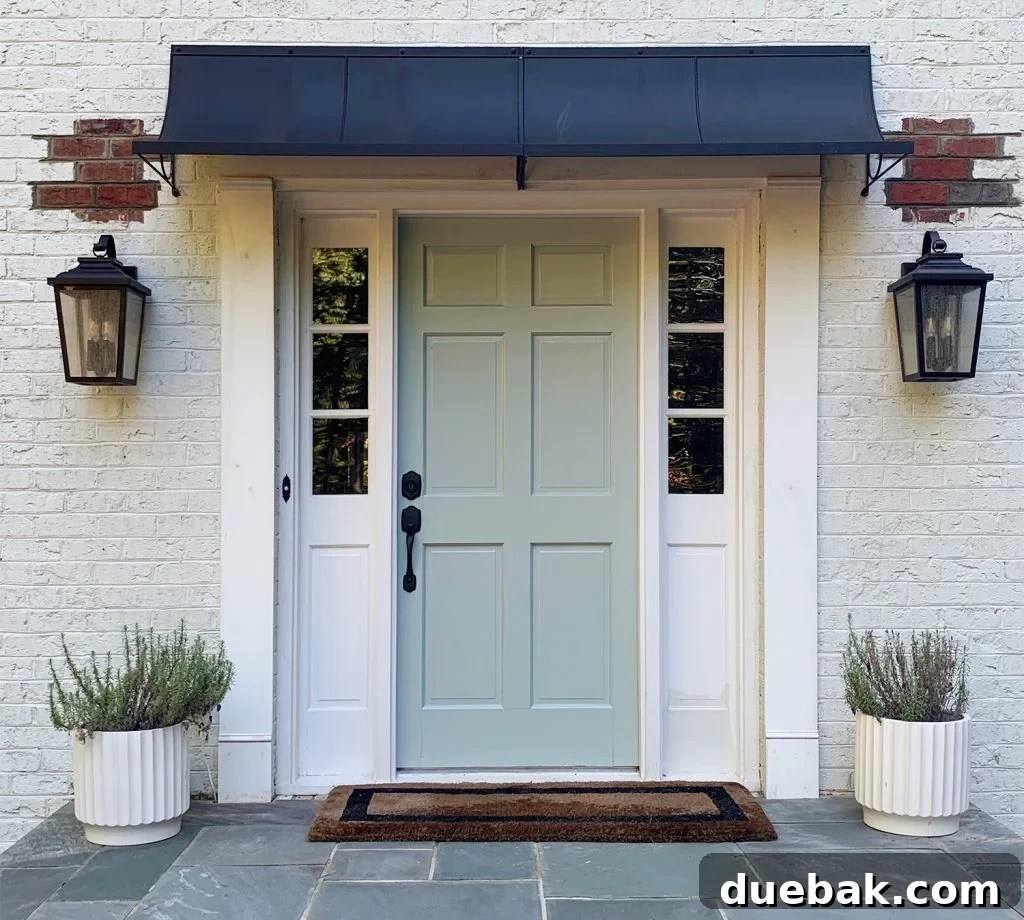 A newly installed modern metal awning over a white house entrance, with visible brick patches and a hint of bluestone