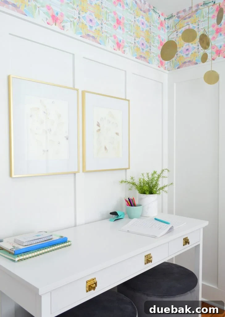 Textural Tides: Wallpaper and Board and Batten in a Beach Bedroom 14 White desk with gold hardware against a board and batten wall, featuring brass frames and a mobile