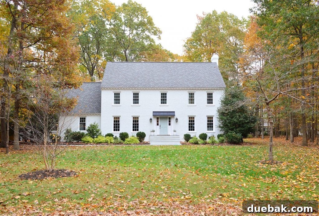 The updated white brick house with new landscaping, including a newly planted tree on the left, enhancing balance.