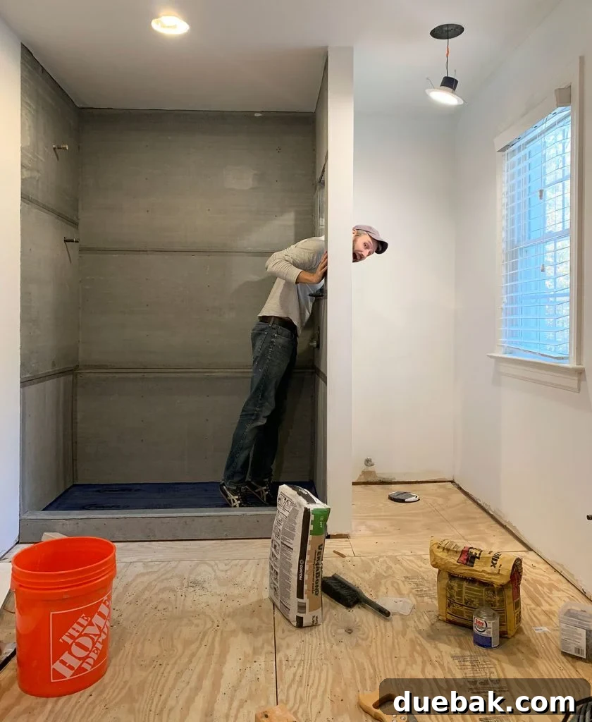 Current progress of the bathroom renovation, showing tiled walls and prepped areas for new flooring.