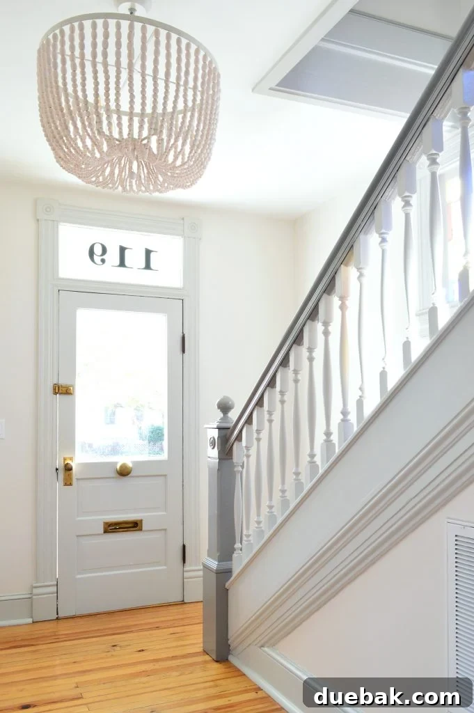 7 Beach House Renovations and the Story Behind Each Space 7 Brightened beach house foyer with a white beaded chandelier and light-colored door