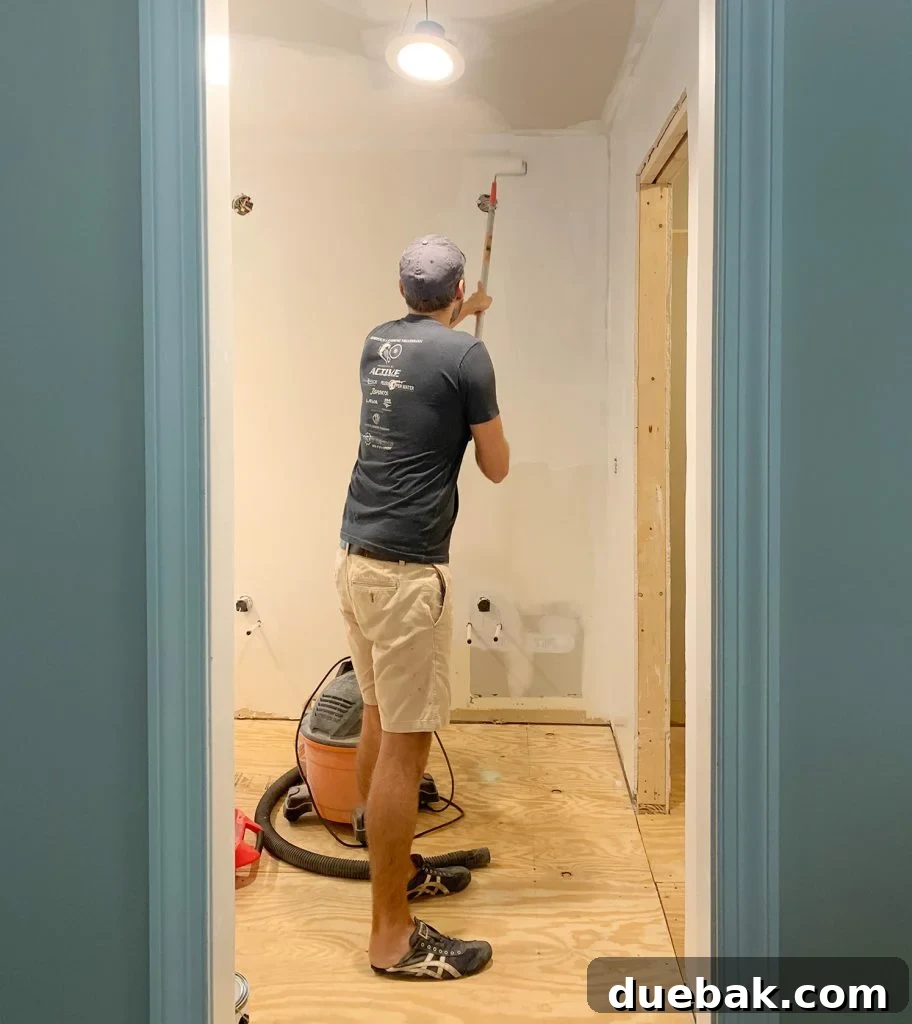 Turning Your Biggest Financial Dreams into Reality 5 Man using a painting extension pole to prime a bathroom wall