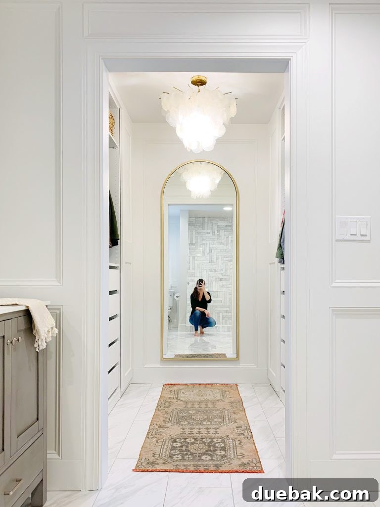 Sherry Selfie In Arched Brass Mirror In Master Closet, showcasing completed floor tile and a glimpse of the double vanity