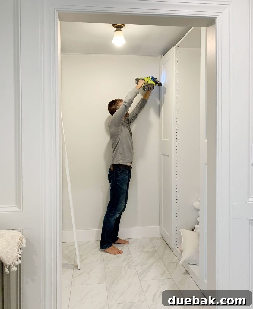 John nailing the first board to build in the IKEA Pax wardrobe, using a Ryobi AirStrike Nailer.