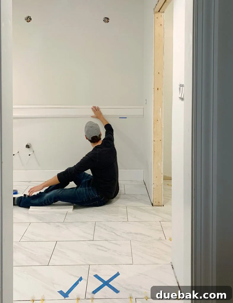Elevate Your Walls with Decorative Molding 6 DIYer John Holding Test Piece of Wall Molding in Bathroom During Installation