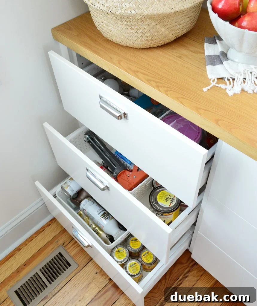 Pantry drawers containing DIY supplies like light bulbs, caulk, and paint
