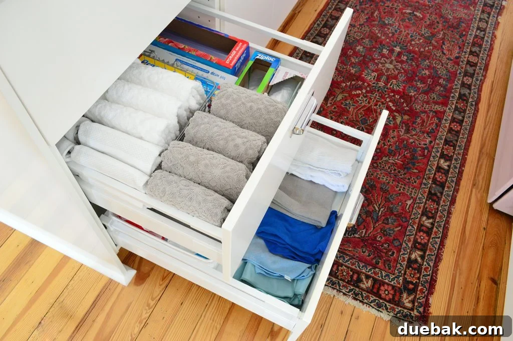 Kitchen drawer filled with neatly folded towels, cloths, and storage bags