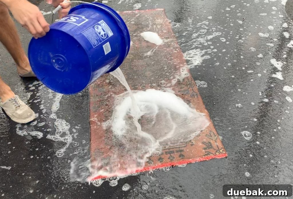 Revitalize Your Rug with a Pressure Washer 5 Soaking a vintage rug with soapy water on the driveway
