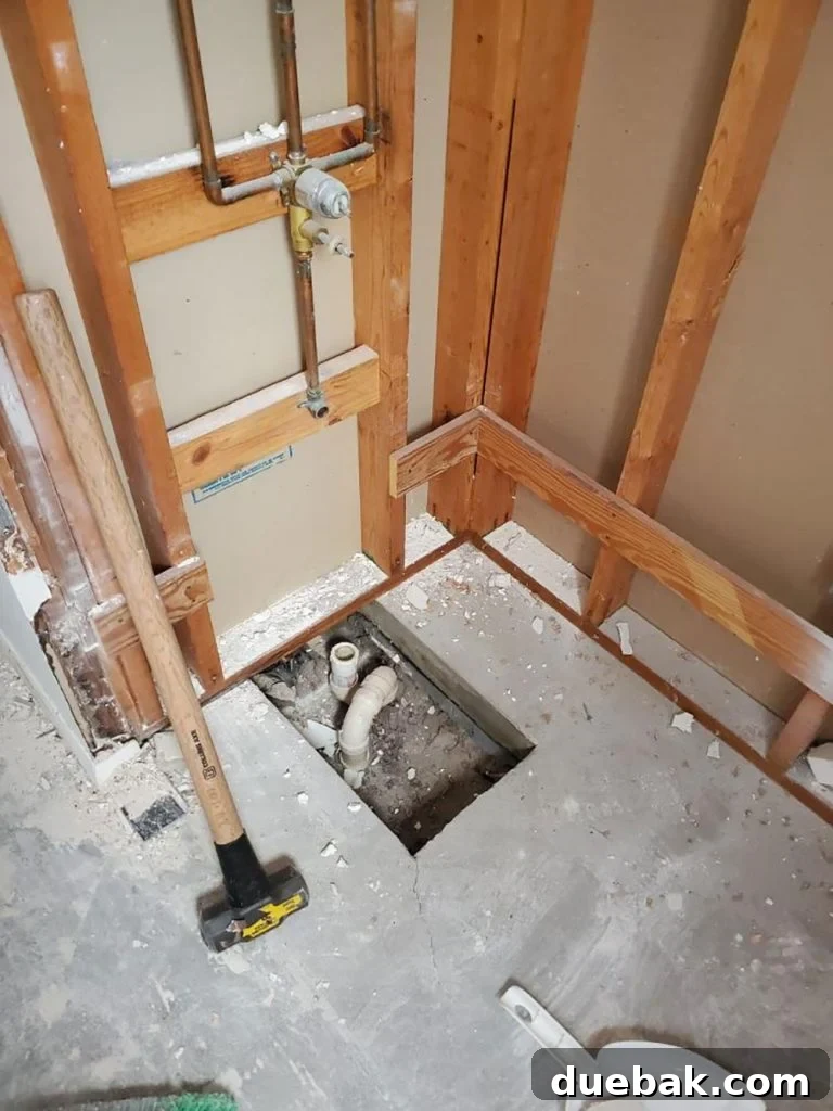 Partially demolished bathroom with exposed pipes and wall, highlighting the renovation work in progress.