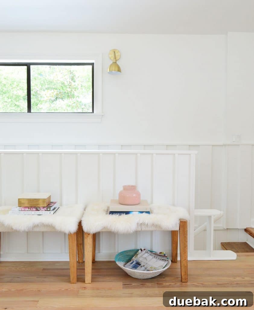 Life in Our Upstairs Family Room Four Weeks In 19 Planked wall next to a staircase featuring decorative benches with faux sheepskin throws and a woven basket, leading down to the lower level, adding texture and warmth to the interior.