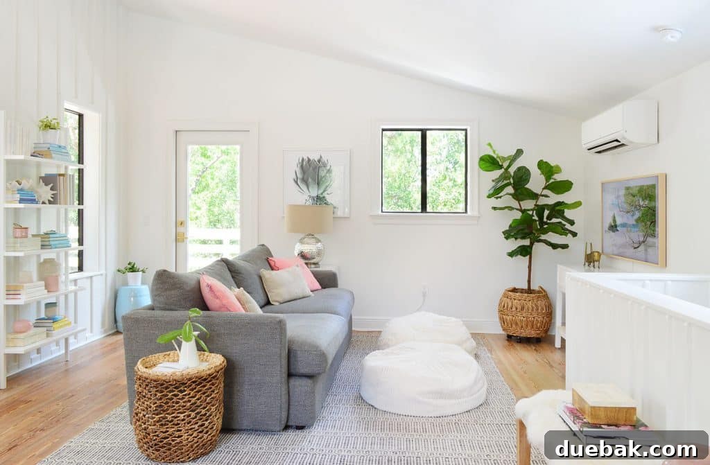 Life in Our Upstairs Family Room Four Weeks In 7 Transformed beachy living room with a gray sofa, soft rug, and a tall faux fig tree, painted in Sherwin Williams Pure White, creating an inviting and serene atmosphere.