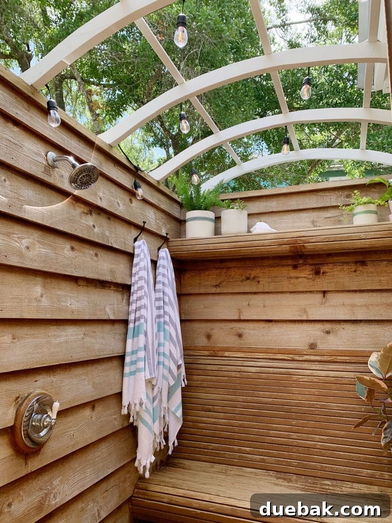 After photo of the outdoor shower, clean wood, new showerheads, and decorative lights.