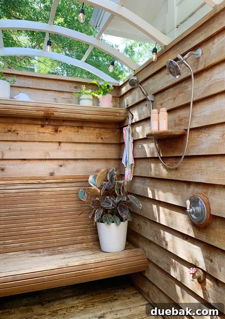 Detailed view of the outdoor shower with new fixtures and lush greenery overhead.