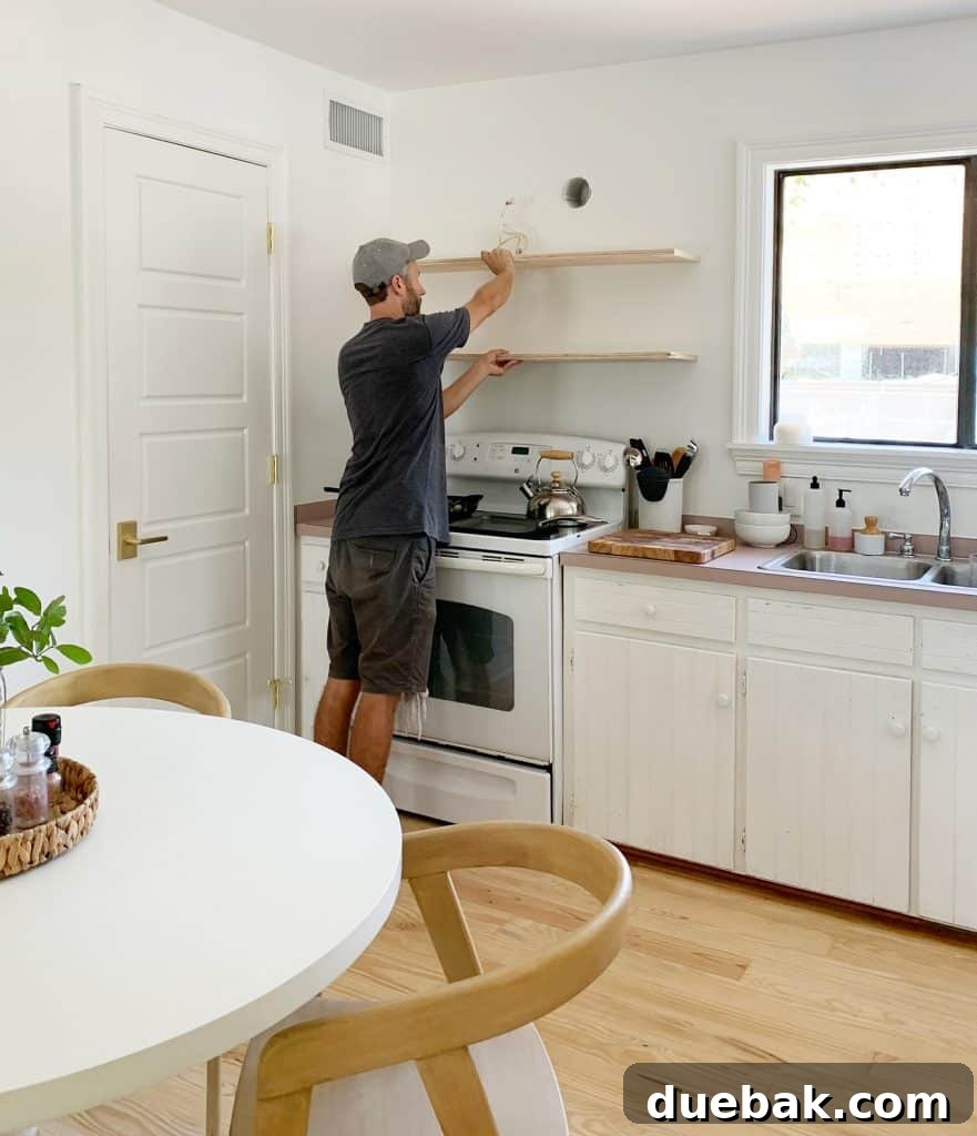 5 Speedy Kitchen Makeovers 21 John Holding Up Plywood Piece To Mock Up Wood Shelf Placement