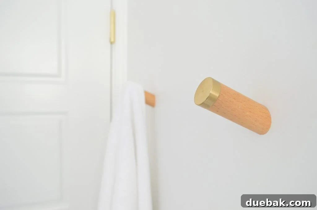 Our Single Bathroom Transformation: Before and After 11 Close-up of wooden towel hooks with brass caps, hanging white towels.