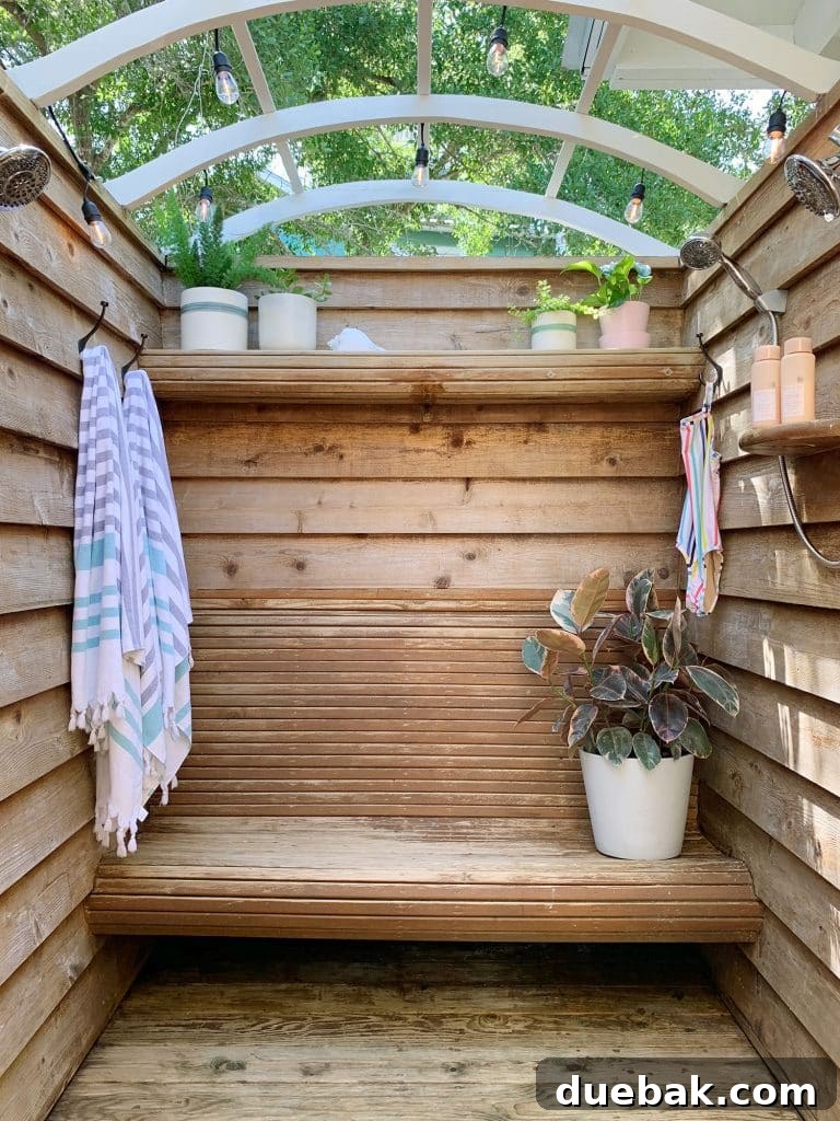 Our Single Bathroom Transformation: Before and After 15 A rustic outdoor shower with wooden slats and lush greenery.