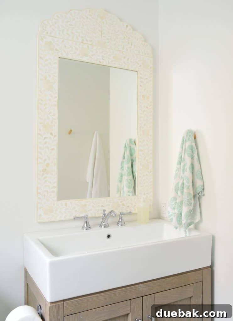 Our Single Bathroom Transformation: Before and After 7 A close-up of the bathroom vanity with a wide sink and a round mirror.