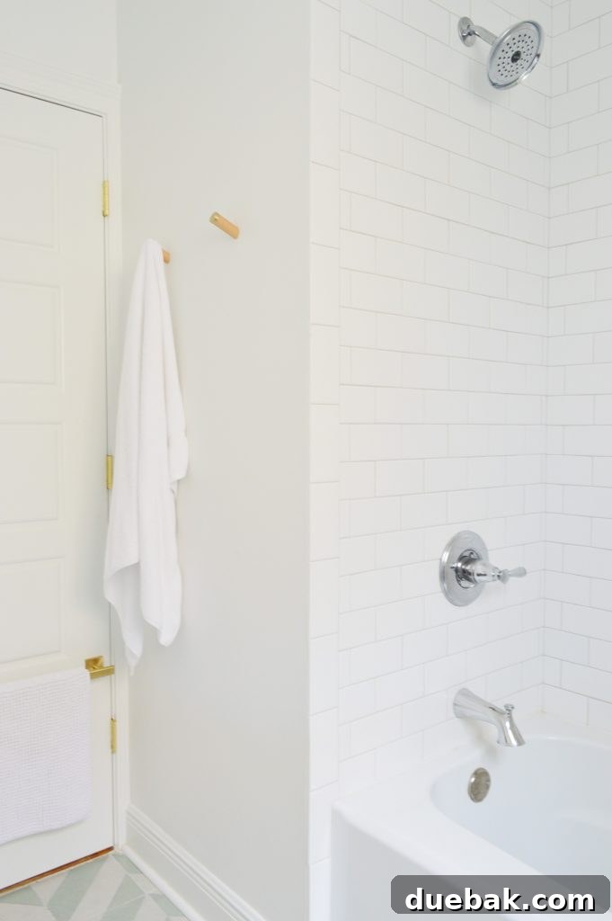 Our Single Bathroom Transformation: Before and After 10 A bathroom shower area with white subway tiles and a playful patterned floor.