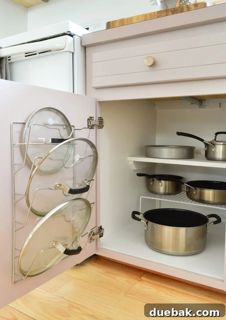 Pots and pans organized in small kitchen with lid mounted on cabinet door
