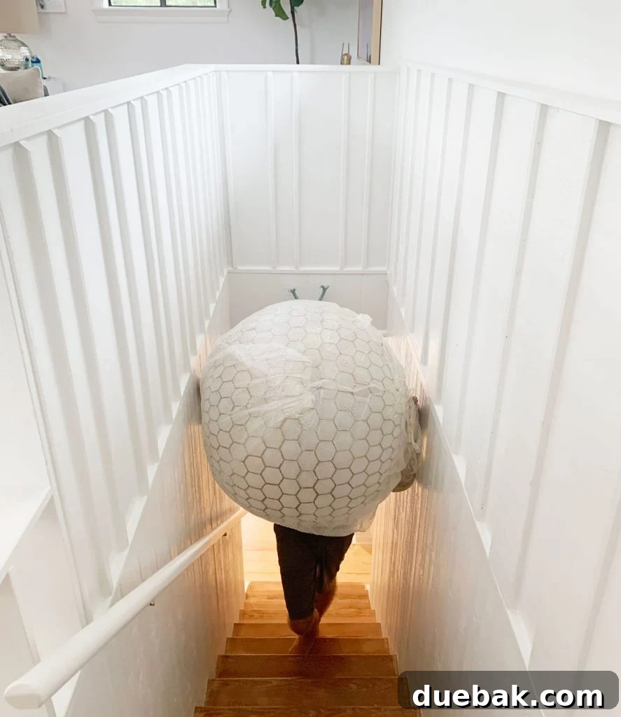 Installing Serena & Lily's Statement Chandelier 5 Oversized Capiz Globe Light Narrowly Fitting Up Stairs, illustrating the challenge of installing large fixtures in tight spaces.