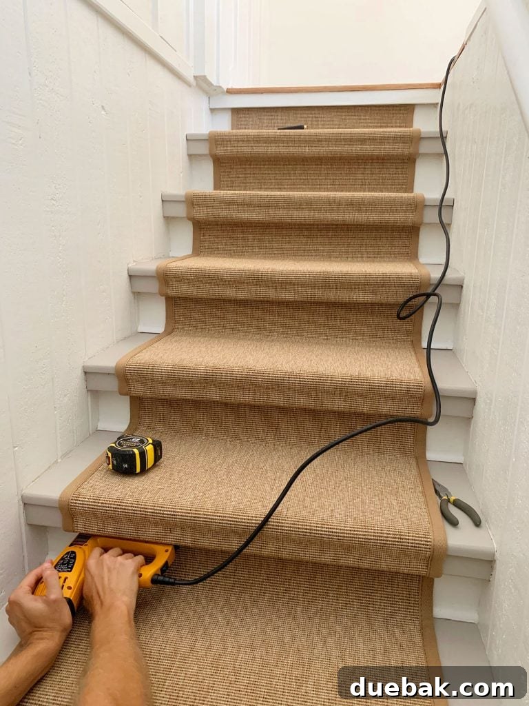 Step Up Your Style: Sisal Stair Runners 11 Hand Pushing Electric Stapler Into Underside Of Stair Tread To Secure Sisal Runner