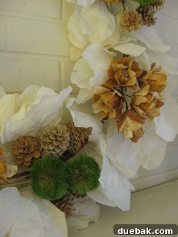 Close-up detail of a white, fresh Pottery Barn wreath with intricate leaves and festive accents