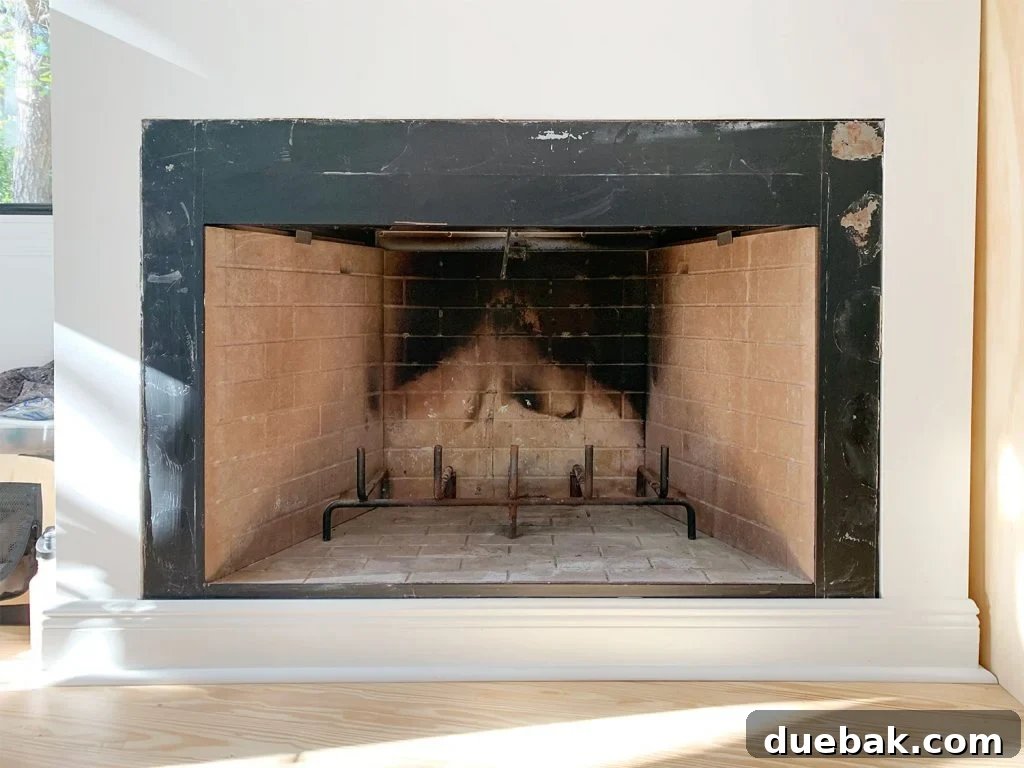 Before photo of fireplace with charred brick interior and patchy black metal surround