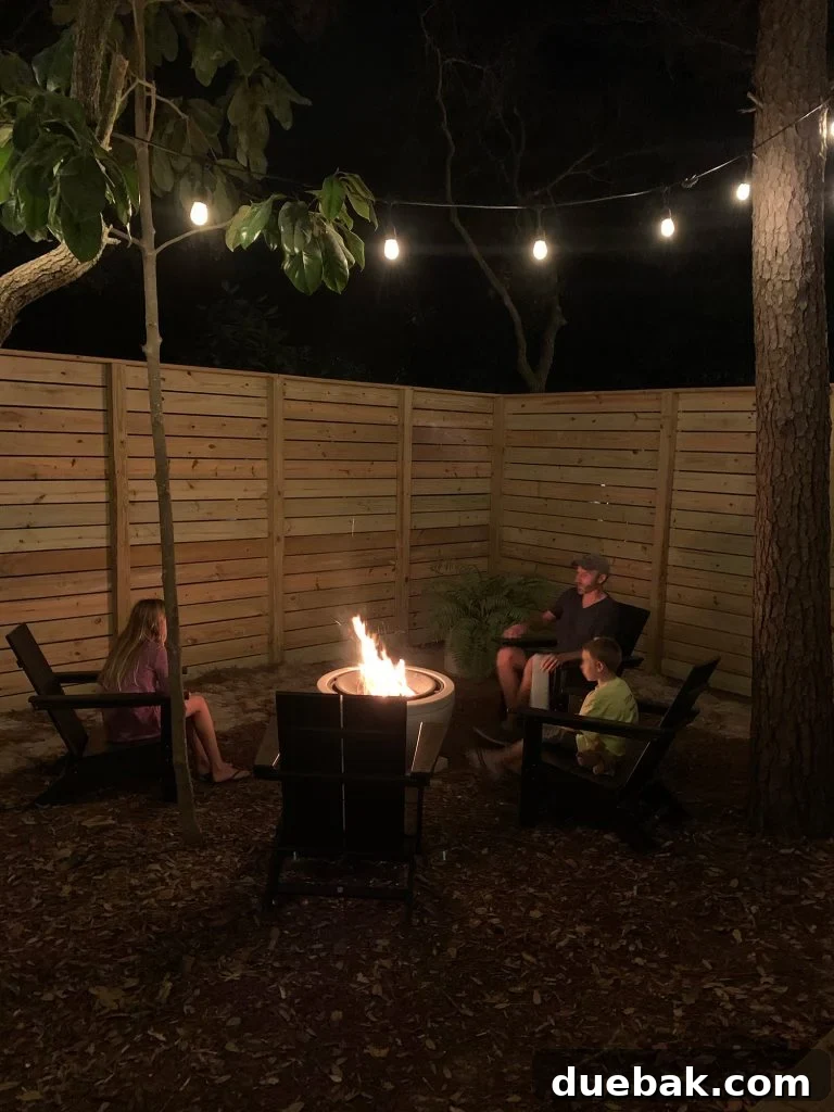 Family sitting around fire pit with unpainted fence
