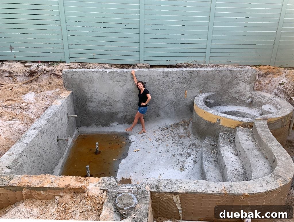 Sherry standing in concrete pool form, providing scale to the construction progress.