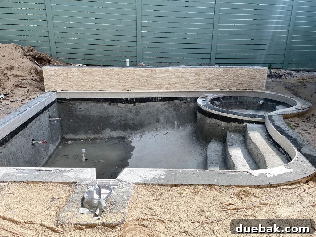 Concrete pool with tile applied around waterline and across accent retaining wall, showcasing meticulous craftsmanship.
