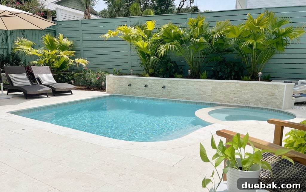Widest view of full pool with round spa stone accent wall with fountains and tropical landscaping DiamondBrite Ivory plaster, creating a resort-like atmosphere.