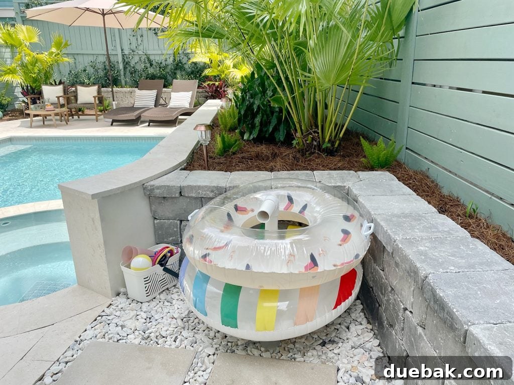 Pool floats organized on PVC pipe stand behind retaining wall, demonstrating a creative storage solution.