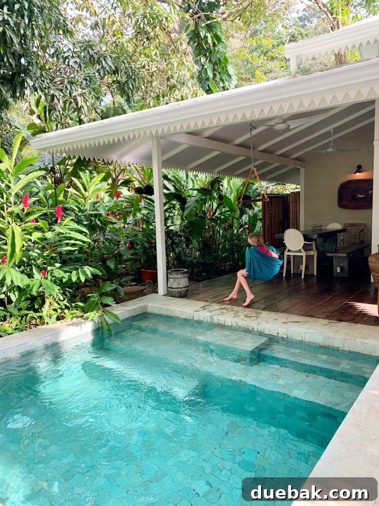 Inspiration photo of small tropical pool next to white house and child in swing, showcasing a serene Bali-inspired design.