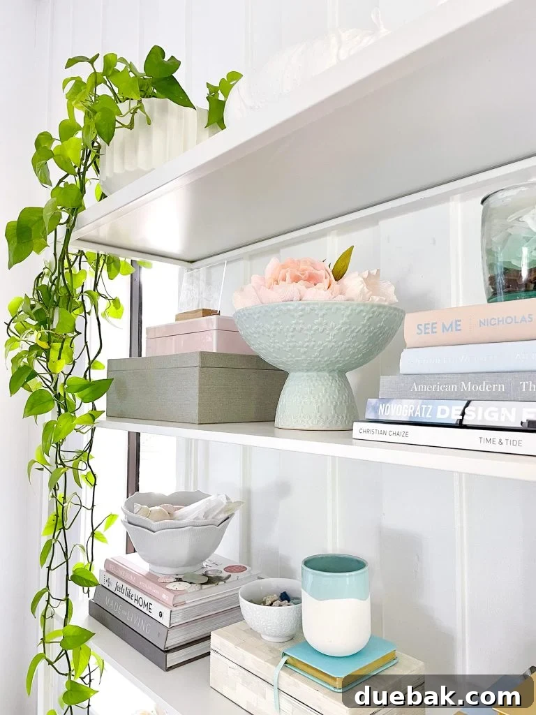 Side View Of Styled Shelves Of Ikea Fjalkinge Bookcase With Stacked Books And Plants