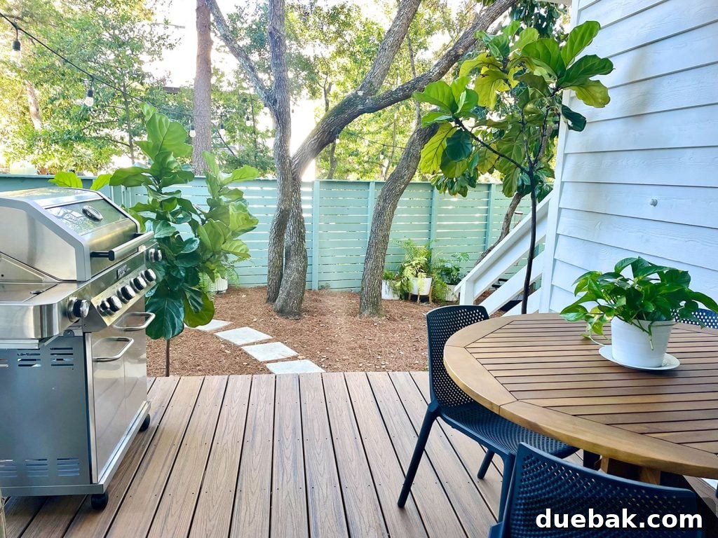View from covered patio with modern grill and outdoor dining table overlooking lush greenery in a well-maintained yard