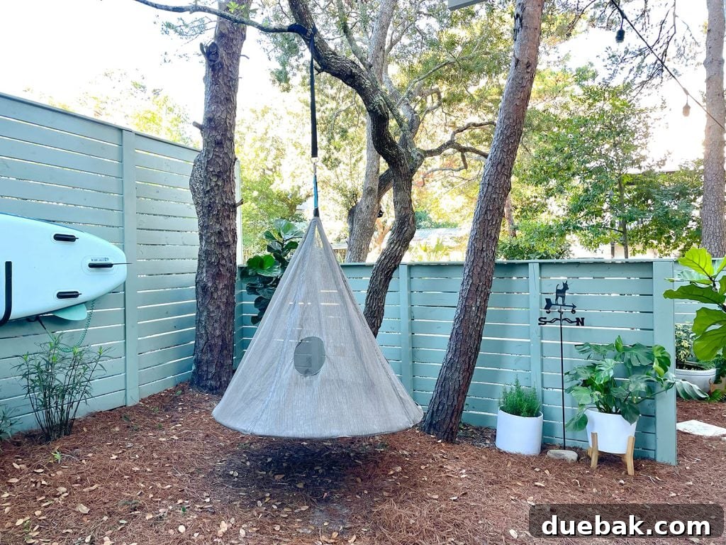 The side yard area, featuring a whimsical hanging tent swing situated near a well-maintained fence, surrounded by greenery