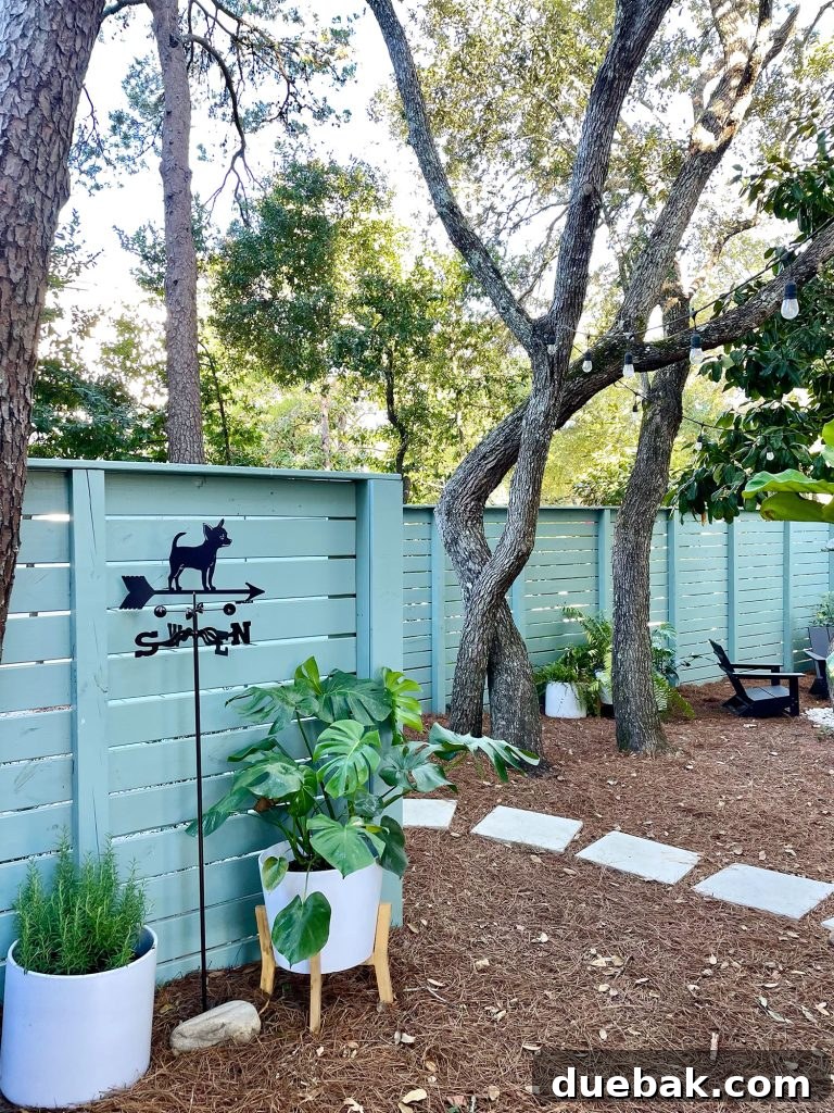 After photo of the firepit area, now featuring a vibrant green fence, neatly potted plants, and a charming chihuahua weathervane